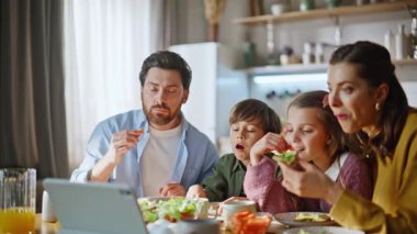 Kahvaltıda sakin aile sabahları yakın çekim yapan gözlemcilerle ilgili. Mutfakta oturup bilgisayar ekranı gibi sandviç yiyen gülen akrabalar. Mutlu ebeveynler çocuklar duygularını paylaşıyor.