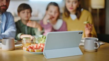 Öğle yemeği yiyen insanlar mutfakta oturup lezzetli sandviçleri yakından yiyorlar. İki dikkatli ebeveyn, çocuk çizgi film seyrediyor, evde yemek yiyor. Mutlu aile hissiyatı Sabah içkisinin tadını çıkar