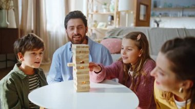 Aile yapımı ahşap kule hafta sonu sıcacık bir apartman dairesi. Neşeli baba, çocuk yaşta anne, masa oyununun keyfini çıkarıyor. Halı döşemesi içeride. Ev içi eğlence konsepti