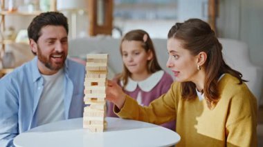 Oyuncu aile, entellektüel mantıksal masa oyununu rahat bir oturma odasında oynar. Duygusal anne baba ve sevgili çocuklar tahta bloklardan kule inşa ediyorlar evde oyunların keyfini çıkarıyorlar. Hafta sonu tatili.