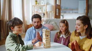 Dört aile üyesi Jenga modern apartman dairesi kapanış oyunu oynuyor. Tahta blok kulesini tutan sevimli küçük çocuk. Neşeli bir aile hafta sonunu birlikte geçirir. Ebeveynlik kavramı