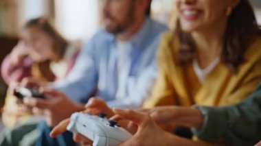 Ebeveynler, çocukların elleri video oyunu kanepede oturup oyun oynarken joysticklere basıyor. Heyecanlı anne, mutlu oğul sanal rekabete seviniyor. Sarılmayı kazan, takım çalışmasının tadını çıkar. Üzgün baba kız duygusu.