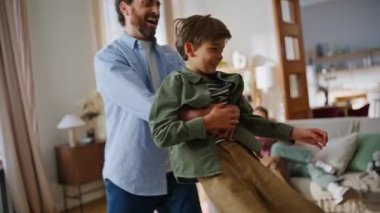 Kaygısız baba dönen oğul evde eğleniyor. Sevgili anne kız kanepede oturup aile hafta sonunun tadını çıkarıyor. Birlikte oynayan mutlu insanlar. Çocuk babası komik oyun ışıklı apartman oturma odası