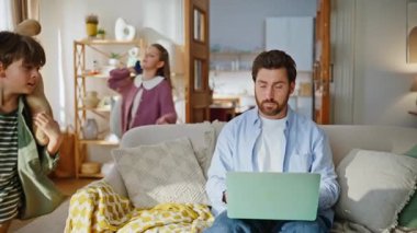 Serbest çalışan baba daktilo eden çocuk bilgisayarlar etrafta koşuşturup gürültü yapan oyuncaklar yapıyor. Sakallı babalarının koltukta oturmasının dikkatini dağıtan oyuncu çocuklar. Sinirli adam uzaktan kumandayla içeride çalışmaya çalışıyor.