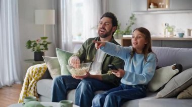 Baba kızı, futbol maçında birlikte kanepede otururken tezahürat yapıyor. Mutlu sakallı adam. Sevimli duygusal genç kız patlamış mısır yiyor. Elinde uzaktan kumandayla televizyon seyrediyor. Aile eğlencesi