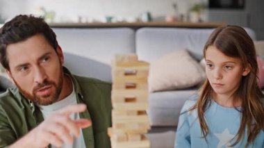 Ebeveyn çocuk modern oturma odasındaki ahşap bloklar inşa etmekten hoşlanıyor. Gülümseyen baba Jenga 'nın güzel kızını yönettiğini anlatıyor. Babacığın genççilik oynuyor..