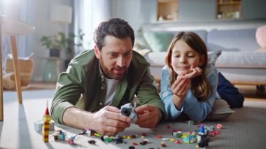 Çocuk babası, oturma odasında yakın çekimde oynuyor. Mutlu sakallı adam baba hafta sonunu sevimli bir kızla geçirmekten bahsediyor. Gülümseyen kız baba lego blokları inşa ediyor İnşaat oyununun keyfini çıkar.