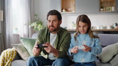 Mutlu kız, babasının evinin kapalı olduğu yerde video oyunu oynayarak seviniyor. Heyecanlı rekabetçi genç kız, babasından gelen zafer gülüşünü kutluyor. Kaybeden koltukta birlikte oturuyor..