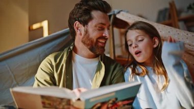 Baba kız battaniyenin altında oturup aile yakınlaşmasının keyfini çıkarmayı tartışıyor. Mutlu gülümseyen baba sevimli genç kızı okuyor ilginç bir hikaye sakin bir hafta sonu evde birlikte vakit geçiriyorlar..