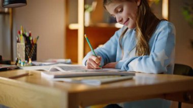 Sorumlu kız notlar hazırlıyor. Evdeki ahşap masa kapanıyor. Gülümseyen liseli kız, ev ödevi dairesini kullanarak konuyu not alıyor. Zeki okul öğrencisi bilgi okuyor..