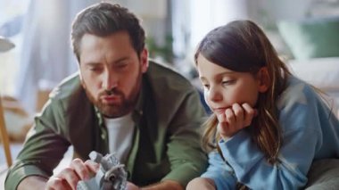 Yaratıcı baba kız oturma odasında lego oynuyor. Gülümseyen sakallı baba, çocukluk çağındaki çocukları öperek birlikte oyun oynamanın keyfini çıkarıyor. Babası okul çocuğu inşaat oyununa karışmış..