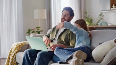 Baba-kız videosu laptopu birlikte otururken arıyor. Gülümseyen sakallı baba mutlu ergen kız sanal buluşmayı selamlıyor web kamerasına bakıyor rahat bir dairede uzaktan konuşmanın tadını çıkarıyor..