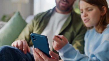Erkek kız cep telefonu izleyip evdeki kanepe kapanışı hakkında konuşuyor. Mutlu baba, apartman koltuğunda oturan genç kıza akıllı telefon gösteriyor. Baba çocuğu cep telefonu internet uygulaması kullanıyor