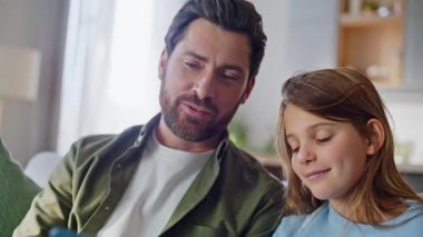 Mutlu çocuk akıllı telefona göz atıyor apartman kanepesinde sosyal medya içeriğini yakından izliyor. Neşeli baba kızı cep telefonuyla rahat koltukta oturuyor. Aile bağları haber kaynaklarını tartışıyor