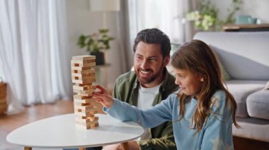 Aile masa üstü oyunu oynuyor. Modern apartman dairesinde sakin bir hafta sonu tatili. Önemseyen baba gülerek, masanın üzerine ahşap kule inşa eden kızı seyrediyor. Mutlu baba genç kız jenga 'nın tadını çıkarıyor.
