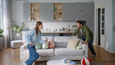 Babası evde kızlık taslıyor, rahat kanepenin etrafında koşuyor. Aktif küçük kız neşeli sakallı babasıyla oturma odasında. Gülümseyen sevimli çocuk hafta sonu eğleniyor. Mutlu aile sevgisi.