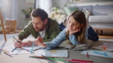Mutlu baba, kızını çizerken evde vakit geçirmekten keyif alıyor. Gülümseyen sakallı baba sevimli çocuk renkli pastel boyalarla çizim yapıyor birlikte yerde yatarken keyifli hissediyorlar. Babalık faaliyetlerini önemsemek.