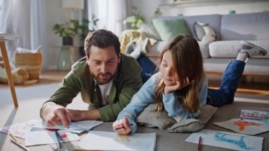 Babam renkli kalemleri kullanarak dairenin zeminini kapatmaya yardım ediyor. Gülümseyen küçük kız çocuk yaratıcı bağ kurma hobisinin keyfini çıkartıyor. Çocukluk eğlencesi.
