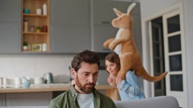 Gürültücü kız, babasının dikkatini dağıtıyor. Oturma odasındaki kanepeye yakın çekimde büyük yumuşak oyuncaklarla oynuyor. Sinirli baba serbest çalışan, genç kızın dikkat dağınıklığından şikayetçi olduğunu savunuyor. Ana çocuk.