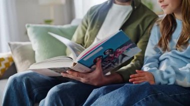 Baba, tapılası kızına sayfaları çevirerek ilginç bir hikaye anlatıyor. Sevgi dolu baba. Kitap okuyan genç kız. Kanepe gevşetiyor..