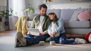 Baba kız tablet ekranlı ev zemininde oturuyor. Gülümseyen sakallı adam ilginç bir çizgi film bilgisayarı arayan küçük kız hakkında konuşuyor. Mutlu baba çocuk eğlence kaynaşması.