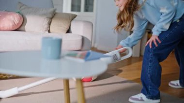 Kız baba, ev bakımında takım çalışmasının keyfini çıkarıyor. Sevimli kız, halıları süpürüyor, gülümsüyor, baba mutfak masasını siliyor, çocuğa sevgiyle bakıyor. Aile temizliği rutini.