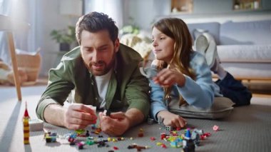 Baba kız daire zemininde lego oynuyor. Oyuncu kız, gülümseyen baba figürünü gösteriyor. Oyun zamanı eğlencesine birlikte vakit geçiriyoruz. Mutlu adam, sevimli çocuk, makyaj ustası..