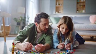 Lego inşa eden baba kız apartmanın zeminini kapatıyor. Gülümseyen sakallı baba, sevimli kızının evde birlikte vakit geçirmesi hakkında konuşuyor. Çocuk mutlu baba inşaatçı oyunundan hoşlanıyor..