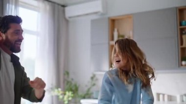 Modern oturma odasında dans eden oyuncu kız babaya yakın çekim. Kaygısız küçük kız gülen adam birlikte hareket ediyor. Ev içi boş zamanlarında enerjik müzik hareketlerinin keyfini çıkarıyor. Komik ebeveyn baba çocuğu.