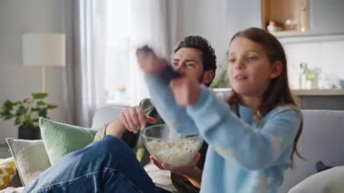 Erkek kız, hafta sonu televizyon izleyip rahat bir şekilde kanepede yan yana oturuyor. Baba elleri patlamış mısır kasesini alıyor genç kız uzaktan kumandaya basıyor ve televizyon komedi programını açıyor..