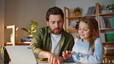 Mutlu bir baba kıza ödev yapmayı öğretiyor online ders tabletine göz gezdiriyor. Gülümseyen baba, uzaktan kumandalı ergen kızını destekliyor..
