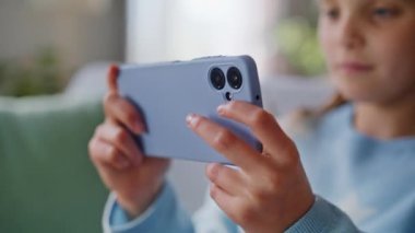 Cep telefonu oyunu oynayan bir kız apartman koltuğunda tek başına oturuyor. Gülümseyen esmer ergen, çevrimiçi eğlence sektöründe cep telefonu tutuyor. Rahat çocuk oyuncu eğleniyor..