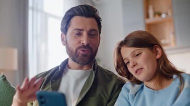 Baba kızı cep telefonu webcam 'ini selamlıyor. İnternetteki iletişim konforunun keyfini çıkarıyor. Sakallı babasıyla akıllı telefon konuşması yapan neşeli bir genç kız. Sanal internet sohbeti.