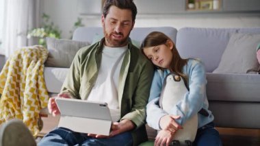 Baba kız, eğitim videosu tableti izliyor oturma odasında oturmuş kanepeyi kapatıyordu. Mutlu sakallı baba, reşit olmayan kız internette gezinme dersi öğreniyor. Ev ortamında konuyu tartışıyorlar.