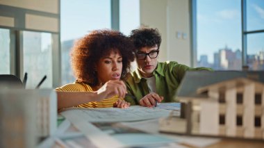 Çok ırklı mimari uzmanlar ofis kapanışında model oluşturma üzerinde çalışıyorlar. Başarılı mimarlar ev planlamasını tartışıyor. Gülümseyen takım emlakçıda konuşuyor.