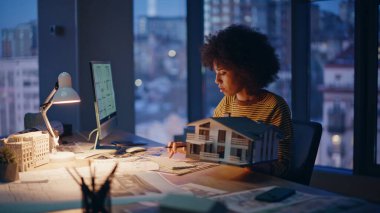 Mimar gece geç saatlere kadar klavyede yazı yazıyor. Ciddi bir Afro-Amerikan kadın mühendis elinde mimari proje geliştirme planı tutuyor. Müteahhit planlama fazla mesai.