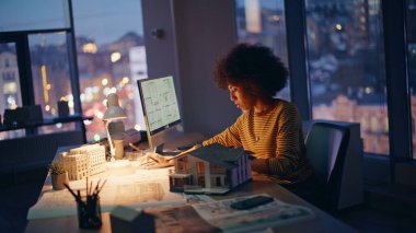 Yapı mühendisi bilgisayar kapanışında geç saatlere kadar mimari planlar üzerinde çalışıyor. Profesyonel Afro-Amerikan kadın mimar analiz projesi. Bina tasarımcısı ev yapısı fazla mesaisi hakkında düşünüyor