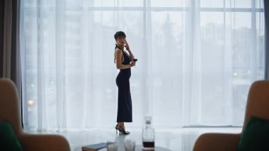 Göz kamaştırıcı kadın akıllı telefondan arıyor. Şehir manzaralı pencereye bakıyor. Parlak geniş bir daire. Ufuk çizgisi alkol içeceği üzerinde çalışan zarif bir model. Kokteyl kıyafetli şehvetli kadın evde tek başına.