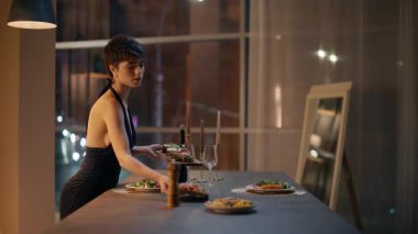 Zarif bir kadın masaya servis yapıyor ve erkekler için romantik bir randevu hazırlıyor. Uzun elbiseler giyen, gece dairesine tabak koyan güzel, kısa boylu bir bayan. Güzel kız yalnız başına güzel bir evde sürpriz yapıyor.