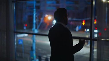 Sinirli adam silueti karanlık ofis çalışma alanındaki cep telefonunu arıyor. Sinirli iş adamı akıllı telefon diye bağırıyor. Son kabinede iş sorunları var. Öfkeli patron geceleri cep telefonuyla konuşuyor.