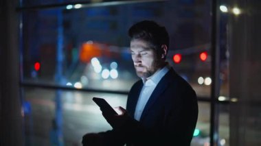 Fazla mesai müdürü cep telefonu ihbarını kontrol ediyor. Rahatlamış adam karanlık siluet panoramik pencere ofis alanında akıllı telefon mesajları okuyor. Zarif patron cep telefonunu tek başına arıyor.