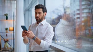 Ofis panoramik penceresiyle e-posta gönderen zarif bir lider. Ciddi bir iş adamı cep telefonundan uzaktan mesaj yolluyor. Cep telefonu kullanan zarif bir iş adamı.