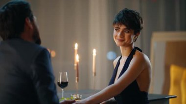 Samimi yemek odasında el ele tutuşan sevgi dolu bir çift. Mutlu çift evde şarap içerek romantik buluşmanın tadını çıkarıyor. Gülümseyen eşler akşam ışığında keyifli sohbetler yapıyorlar. Aile yaşam tarzı