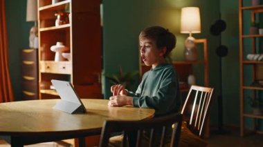 Çocuk elinde tablet fotoğraf makinesiyle apartman masasına merhaba diyor. Sevimli küçük öğrenci çevrimiçi buluşmayı selamlıyor. Konuşan bilgisayarlı webcam uzaktan sohbetin tadını çıkarıyor. Sanal konferans konsepti.