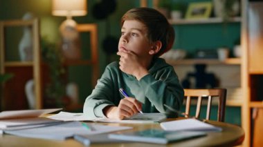 Düşünceli çocuk not defteri yazarak ders çalışıyor. Matematik problemini çözen, notlar alan zeki bir öğrenci. Zeki ilkokul öğrencisi işyerini öğreniyor..