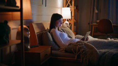 Uykulu kadın lamba lambasındaki yatak odasında tablet arıyor. Rahat bir genç esmer, tek başına yatmadan önce film seyrediyor. Elinde dijital cihaz olan sakin bir bayan teknolojinin tadını çıkarıyor..