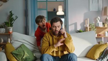 Oğul, babasının cep telefonunu aramasını engelliyor. Evdeki kanepeyi kapatıyor. Stresli sakallı adam akıllı telefondan konuşuyor. Küçük gürültücü çocuk kanepede koşuşturup bağırıyor. Babalık sorunu.