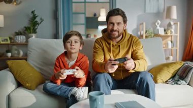 Baba oyuncu yarışmayı kazanır. Başarısızlığa duygusal tepki veren küçük oğlunun heyecanını hisseder. Mutlu baba video oyunu zaferine seviniyor üzgün çocuk koltukta hayal kırıklığına uğramış yastığa çarpıyor..