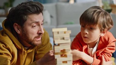 Baba çocuk Jenga 'yla yarışıyor. Dairenin zeminini kapatıyorlar. Gülümseyen sakallı adam, konsantrasyonlu tahta bloğu çekiyor sevimli oğlu oyuncu babayı destekliyor. Aile oyun geliştirme evi.