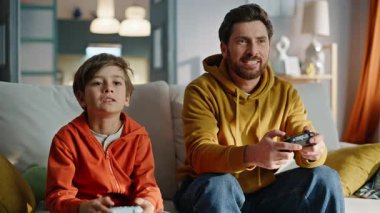 Gülümseyen baba video oyunu kazandı. Stresli küçük çocuk sinirli hissediyor. Mutlu babaya yakın çekimle vuruyor. Rekabetçi ebeveyn çocuk kanepede oturarak sanal yarışma oynuyor. Duyguları kontrol sorunu